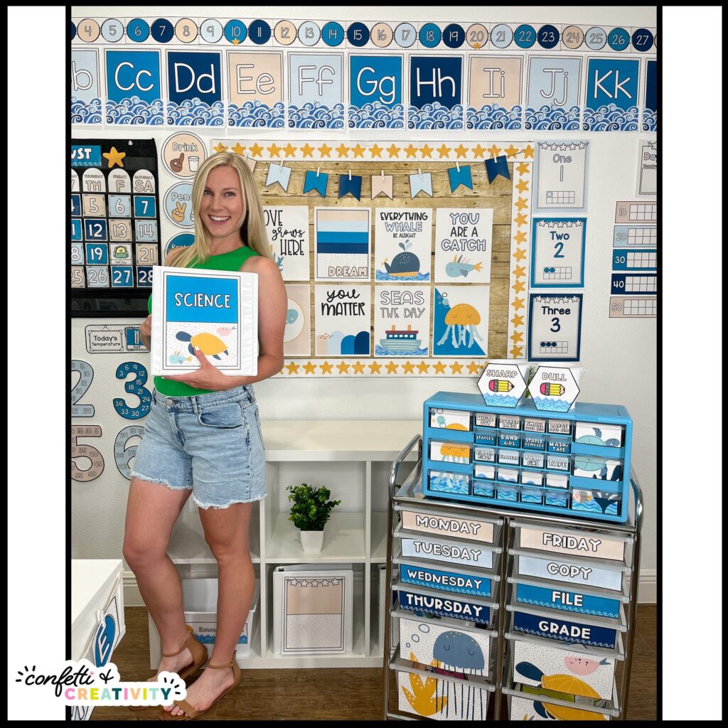 Shows Megan holding a binder cover with a starfish on it and the rest of the classroom is decorated with the ocean themed classroom decor bundle. Features plenty of ocean clipart, blue colors, and so much more to set up an ocean themed space.