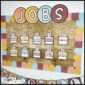 Shows the modern neutral classroom jobs set up on a bulletin board in a real classroom