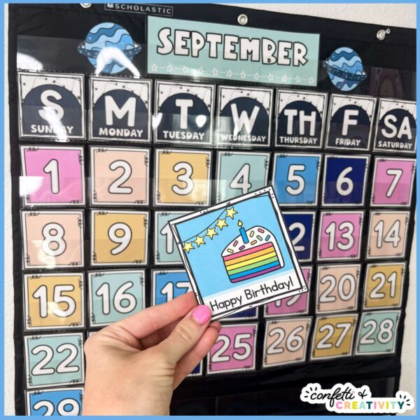 Space Classroom Calendar Pack 4 Shows the classroom calendar in a black pocket chart, while holding a holiday card for a birthday