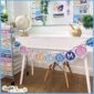 Shows an example of the space welcome banner on a white desk. The banner is held together by twine and clothespins, and the rest of the space classroom decor is in the background