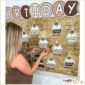 Shows Megan setting up the birthday board holding a clipart set of cliaprt