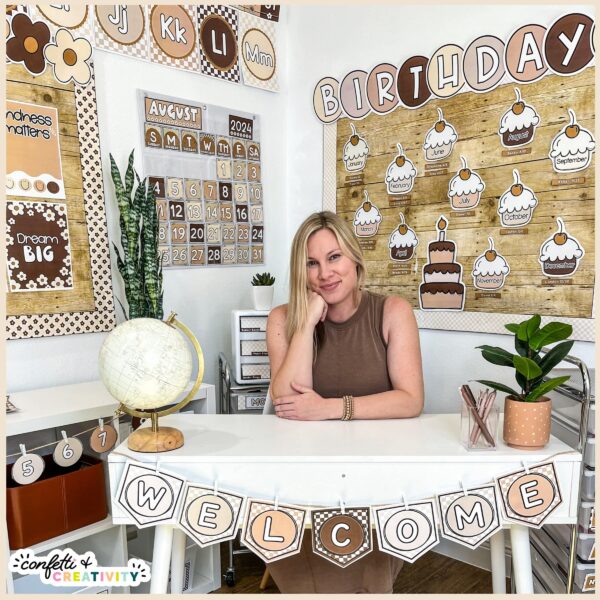 Neutral Classroom Decor Bundle - Megan Sitting in Classroom Surrounded by the Neutral Classroom Theme Shows Megan sitting in a corner of the Neutral Classroom Theme. Features the birthday board and a white desk Megan is sitting at